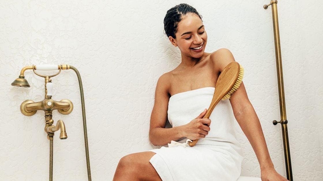 Lady dry brushing during her beauty routine for detoxification and lymph drainage
